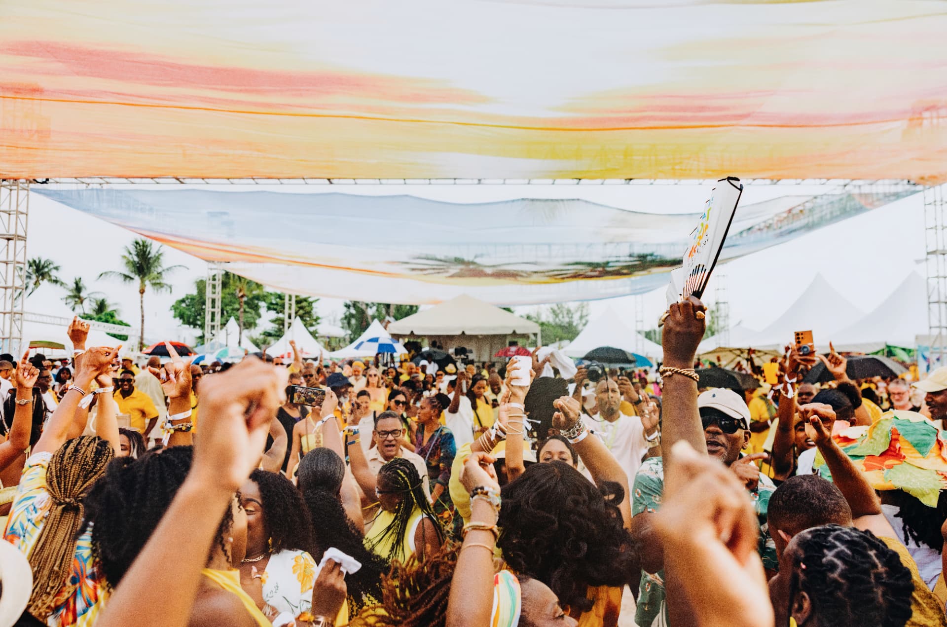 A joyful crowd in yellow dancing at the Rum Breakfast beach party in Barbados