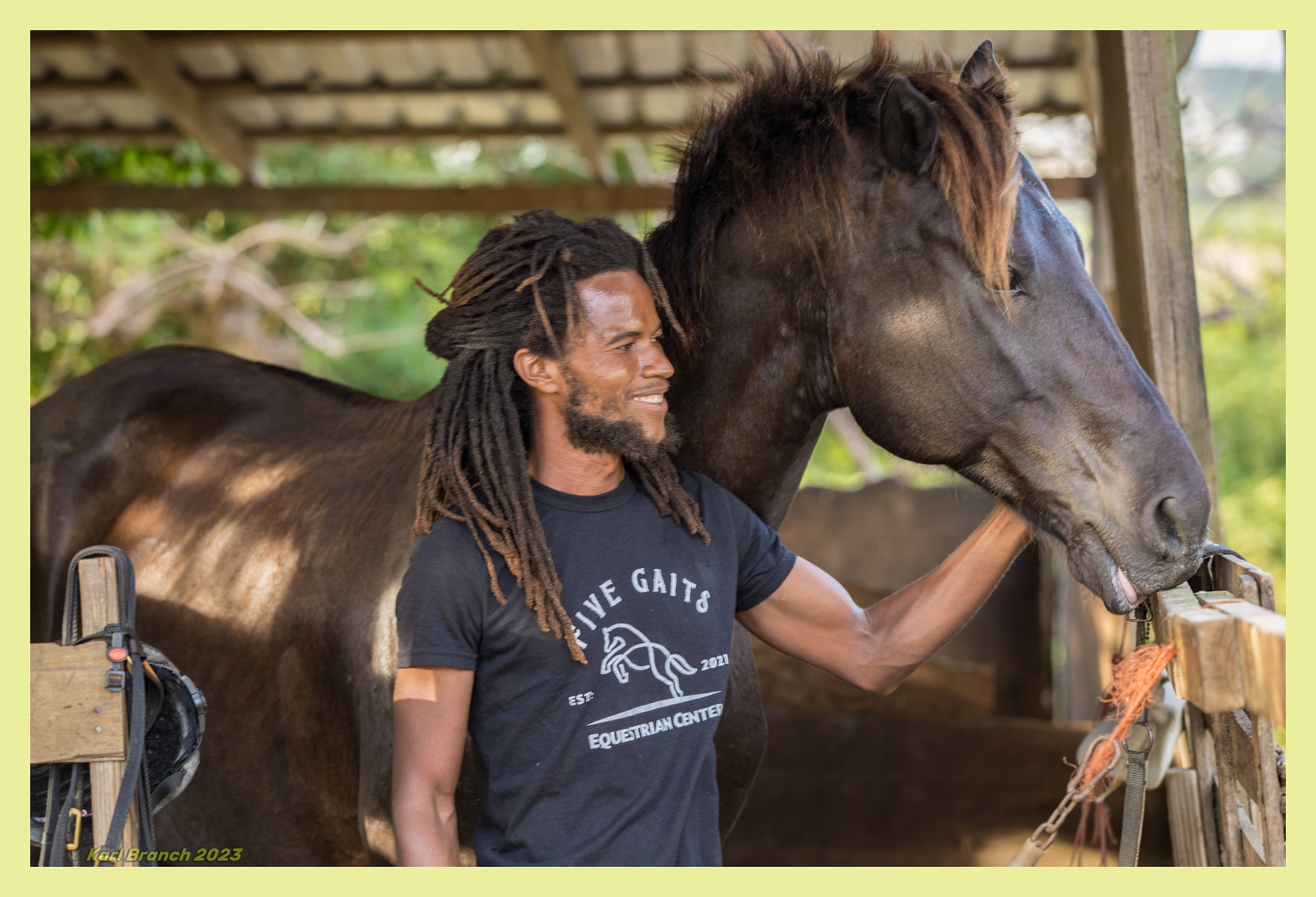 A Barbadian horseman smiling beside his horse at an equestrian centre