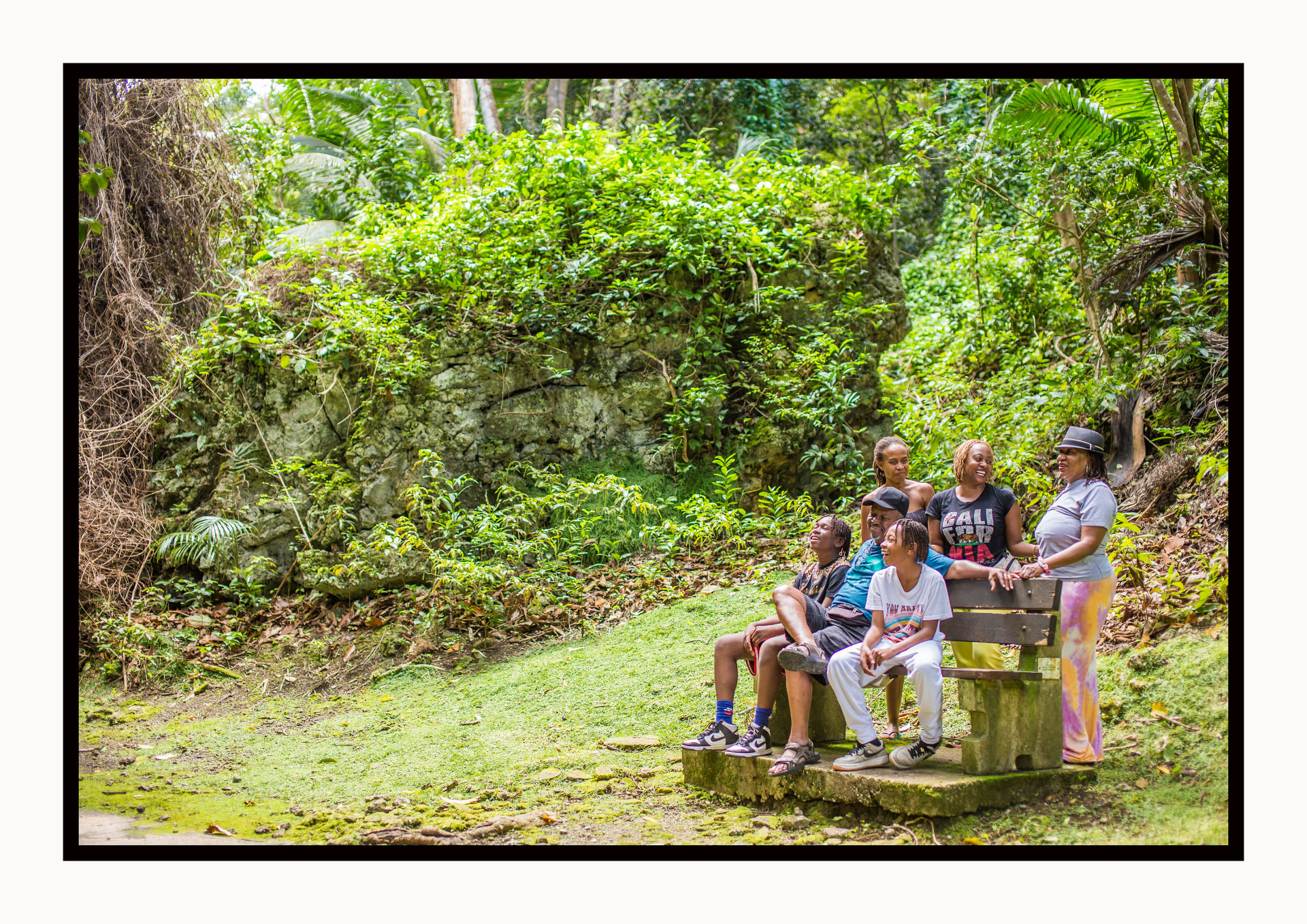 A family laughing together on a bench in the lush Barbados forest